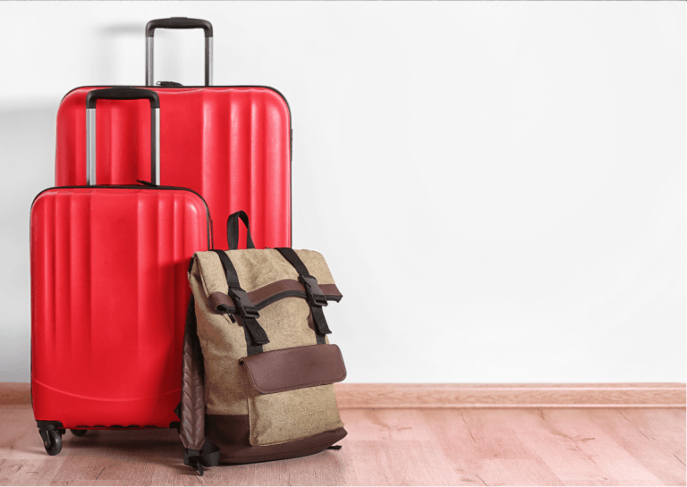 A large red suitcase, a small suitcase, and a brown backpack standing together on a light-colored wooden floor against a white wall.