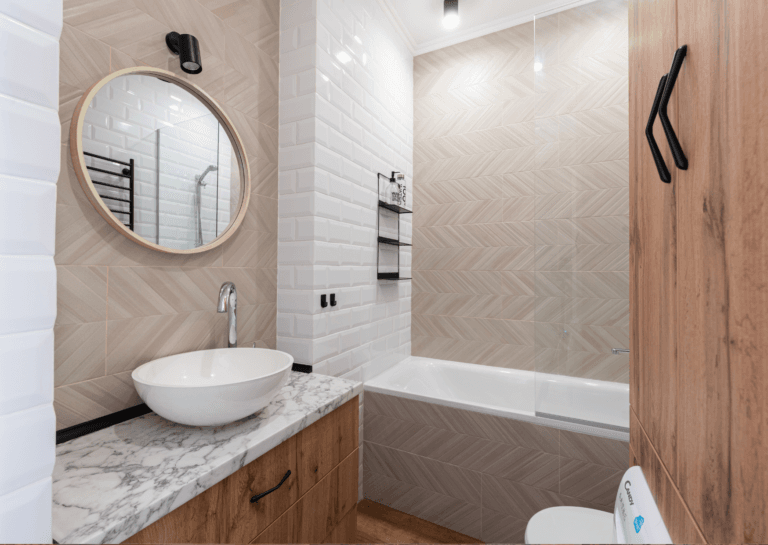 Bathroom decor with a round sink and mirror on the left and a bathtub against the opposite wall.