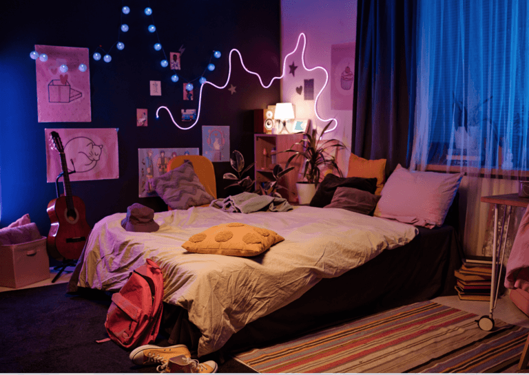 A darkened bedroom with a bed decorated with pillows in various colors. A guitar and a pair of shoes sit beside the bed. Soft light blue tones frame the scene on the left and right, with drawings and a winding light spiral adorning the walls, creating a cozy and artistic atmosphere.