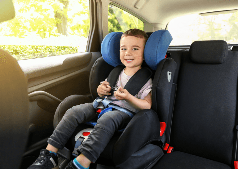 Toddler boy sitting in a car seat in the back of the car, captured from the front seat, enjoying the ride.