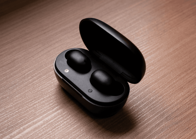 Black earbuds in an open charging case, showing the earbuds inside, placed on a close-up wooden surface, highlighting their sleek design and convenience.