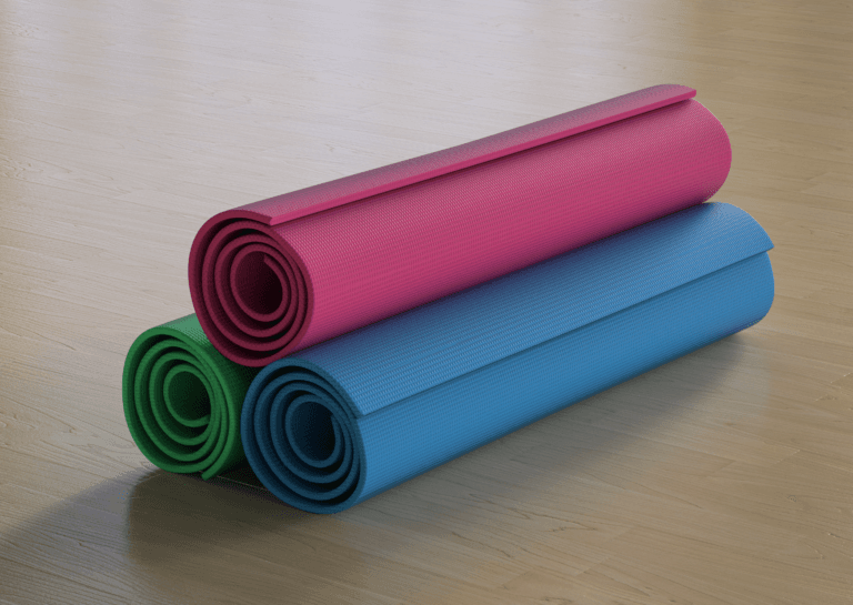 Three rolled foam mats stacked on a light wood floor, with red on top, followed by green and blue mats.