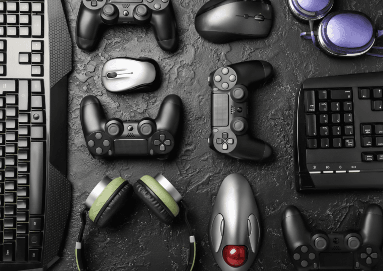 Gaming accessories arranged on a dark surface, featuring black keyboards, mice, game controllers, and headsets.