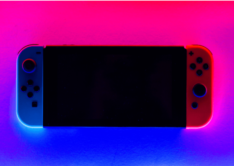 Close-up of a Nintendo Switch gaming console, prominently displayed against a gradient background transitioning from red to blue, creating a vibrant and dynamic visual effect.