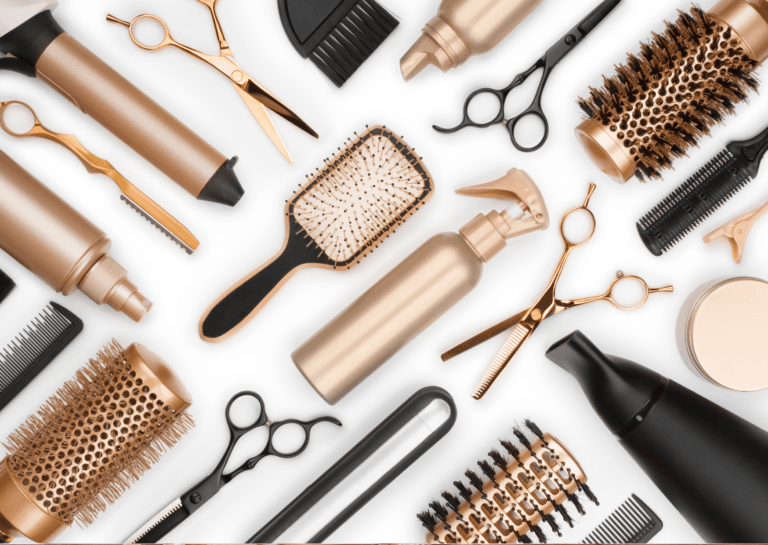 Hair products displayed on a white background, including a hairbrush, flat iron, hairdresser scissors, and combs in sleek black and gold colors, emphasizing a stylish grooming setup.