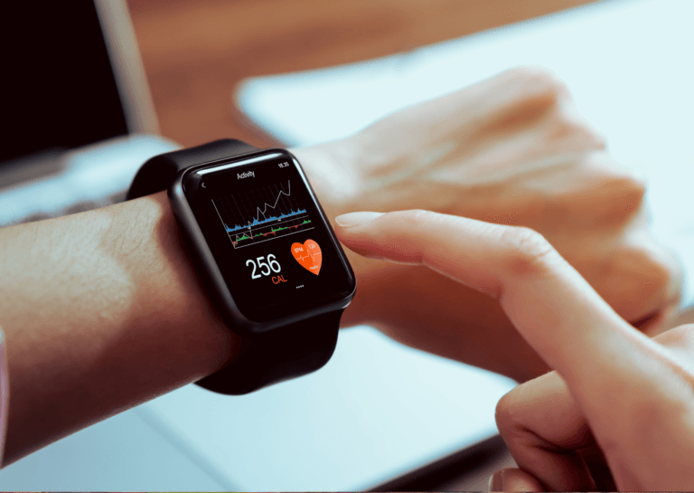 Close-up of a person's forearm wearing a health monitoring smartwatch displaying a colorful graph, 256 CAL, and a red heart icon showing the heart rate at 120 bpm.