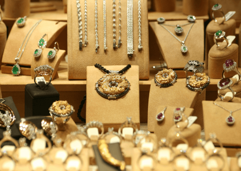 A beautiful display of various jewelry pieces, including rings, bracelets, and necklaces, all set in a warm gold-colored atmosphere. The elegant arrangement highlights the intricate designs and luxurious shine of the accessories, creating a sophisticated and inviting look.