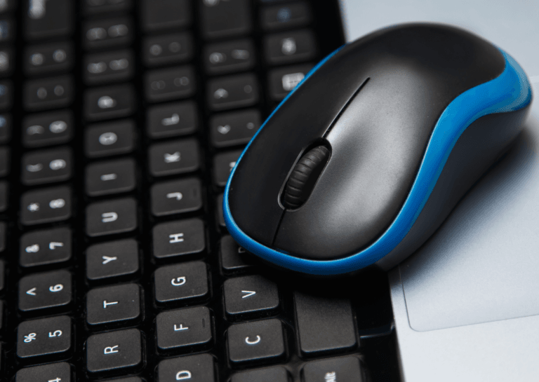 Close-up of a black wireless mouse with a blue trim resting on a black keyboard.