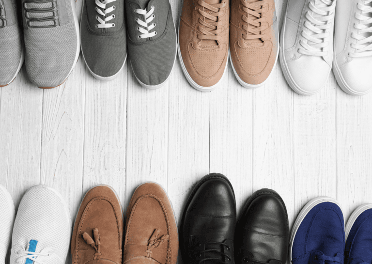 A collection of men's sneakers in diverse colors arranged on a white floor, with their toes pointing towards each other. This vibrant display emphasizes the variety of styles and shades available, creating an eye-catching focal point for sneaker enthusiasts.