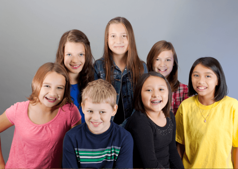 Seven children aged 8 to 12 posing and smiling for the camera.