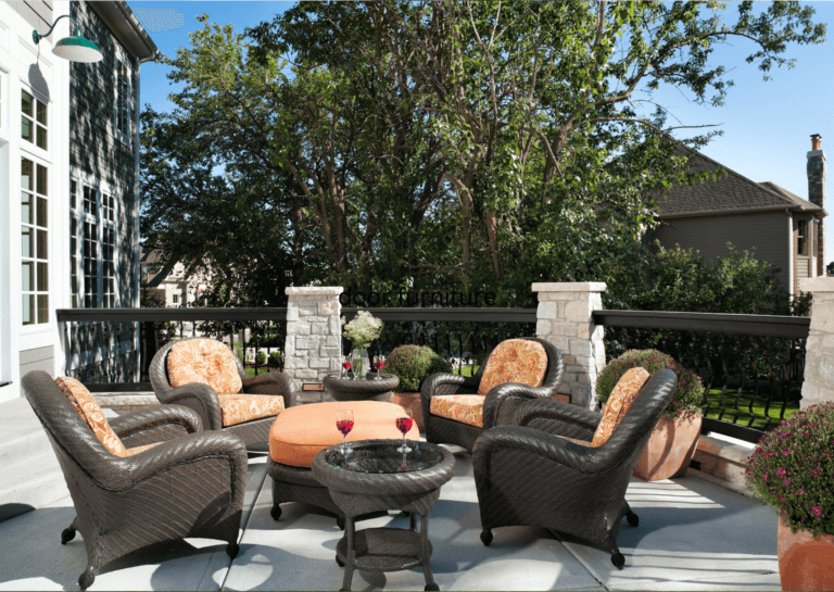 Luxury outdoor furniture with rounded edges, brown frames, and orange cushions on a finished terrace with a decorative railing and pillars.