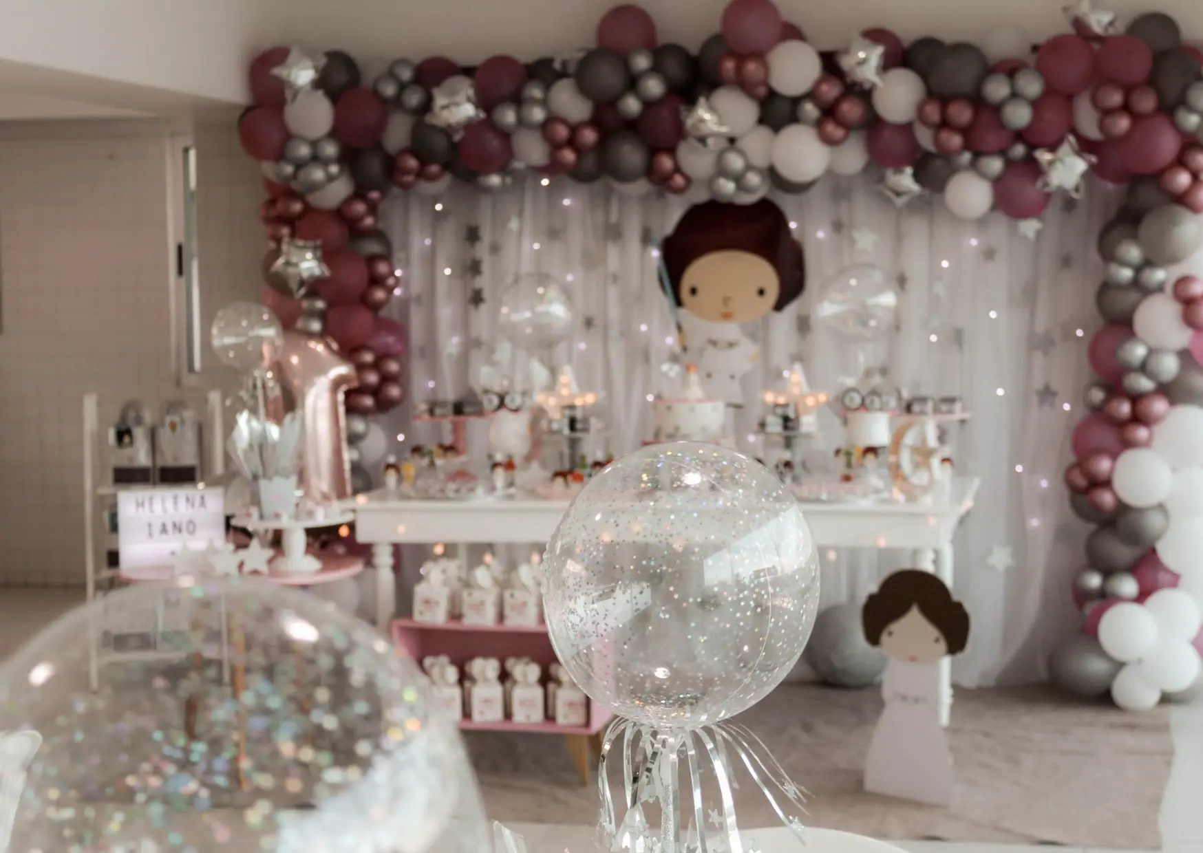 Party decorations featuring a balloon arch over a table decorated with various festive items.