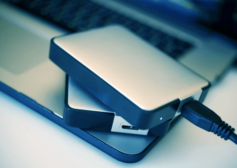 Two glossy black portable drives resting on a laptop, showcasing their sleek design and compact form factor.