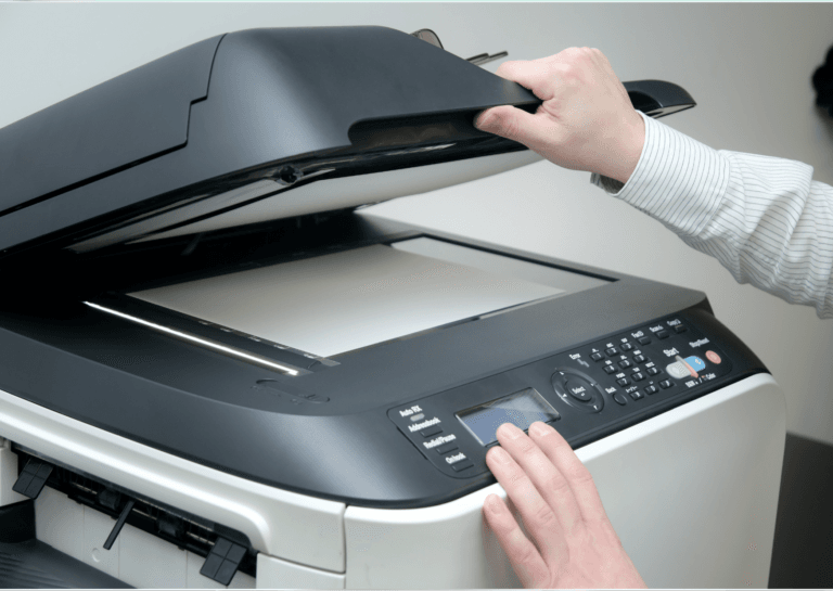 Man operating a large office scanner, opening the lid with his right hand while using his left hand to adjust the control panel.