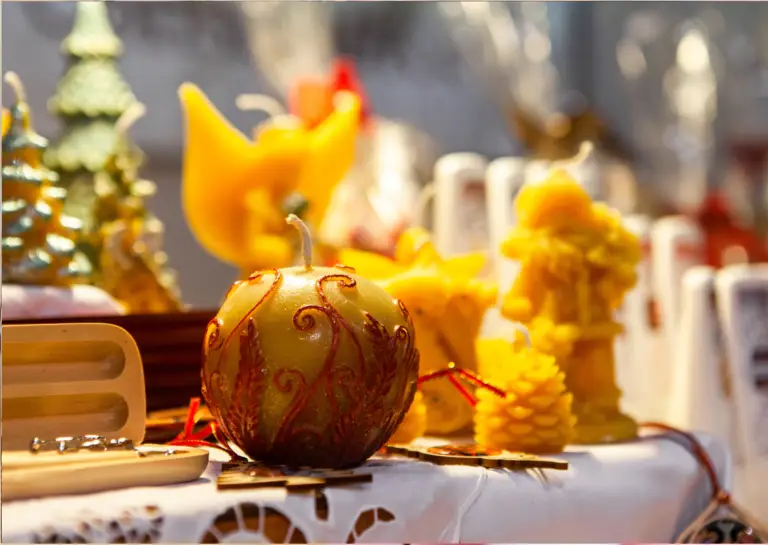 Close-up of Christmas decor on a table with a tablecloth, centered around an apple-shaped, elegantly decorated candle.