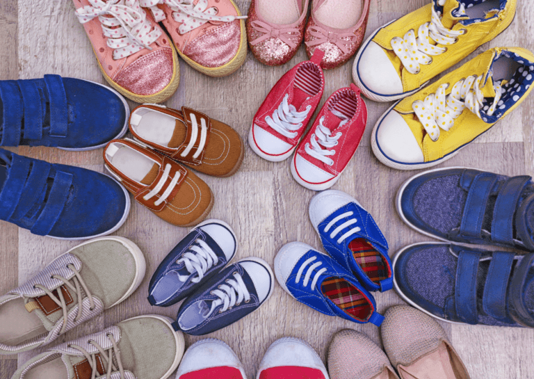 Various sneakers arranged in a circle with adult shoes on the outer ring and toddler shoes on the inner ring, toes facing inward.