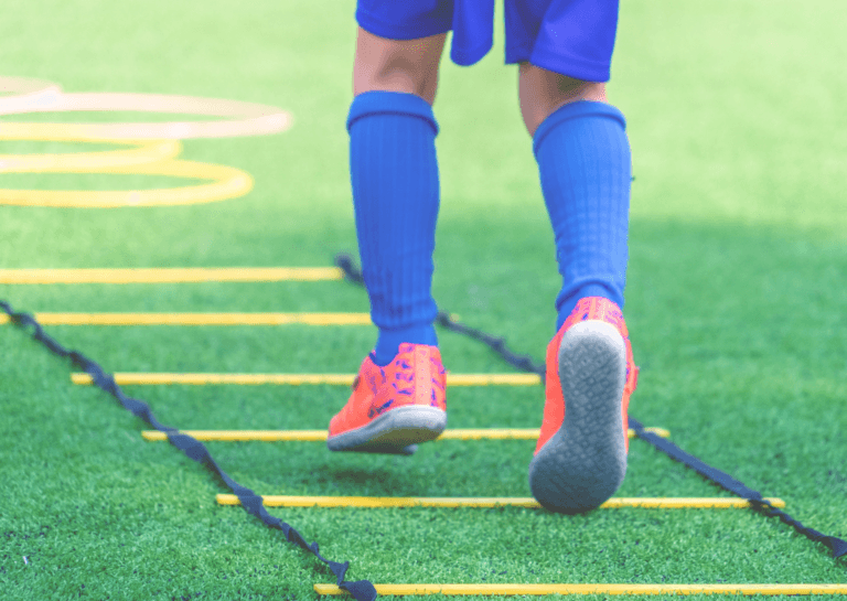 A person running on grass while using speed agility training tools, demonstrating dynamic movement and athleticism.