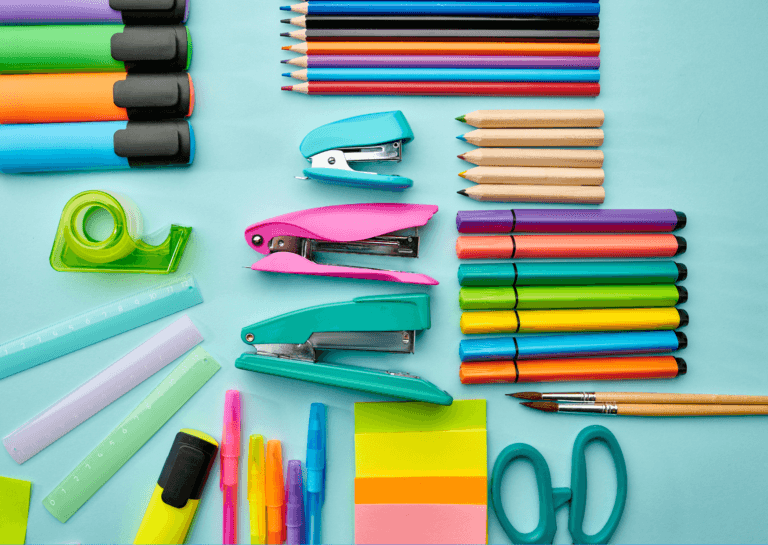 Light blue background featuring a variety of stationery supplies, including colored pencils, markers, scissors, and staplers, all neatly arranged in different sizes on the surface.