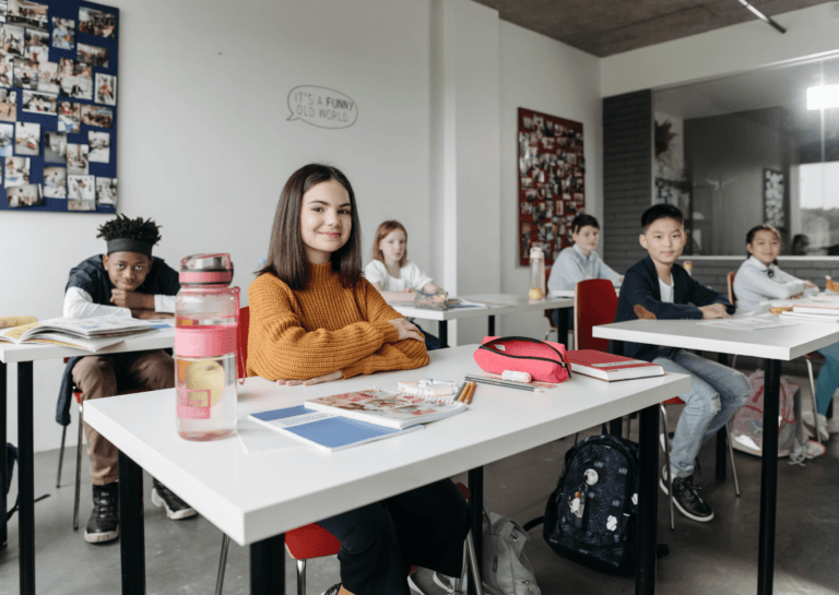 Study desk and chairs for kids, featuring six teenagers sitting behind their desks in a classroom, all looking at the camera.