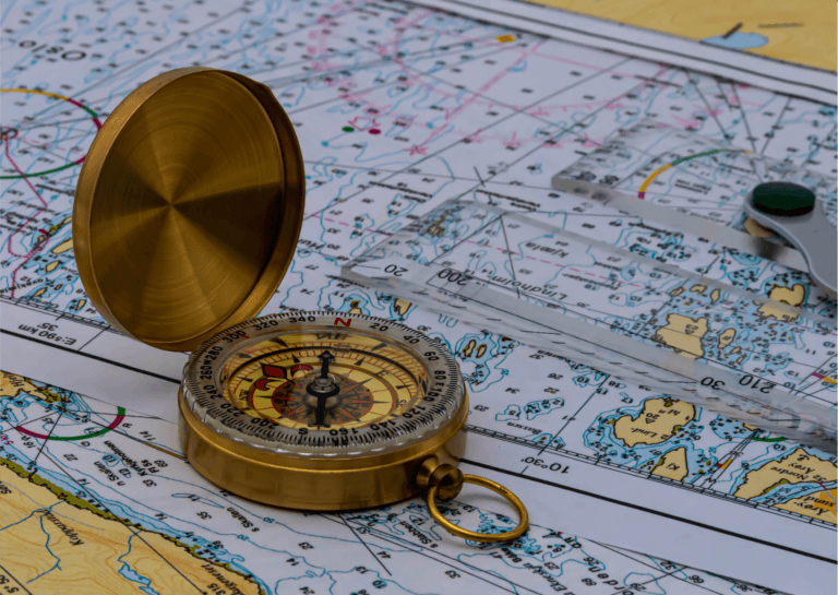 Open gold compass resting on a topographical map, displaying elevation markings of the surrounding area.