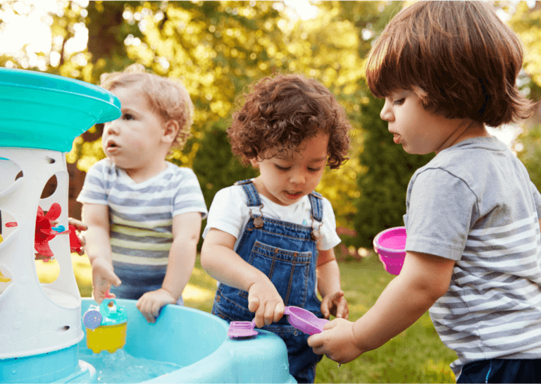 Three toddlers playing at a water table, captured at their shoulder height, engaged in fun activities.