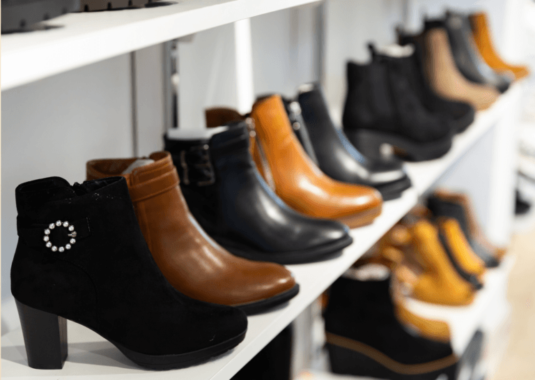 A stylish assortment of ankle-high heeled shoes displayed on a white shelf within a shoe store. The clean backdrop highlights the elegance and variety of the footwear, making it an attractive feature for shoppers seeking fashionable options.