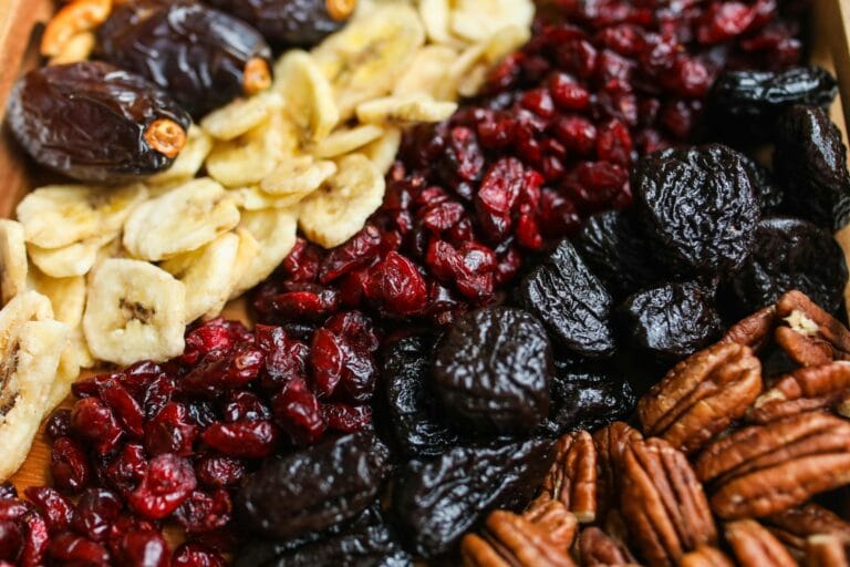 Close-up photo of dried banana slices and assorted other dried fruits neatly arranged in a row, showcasing their vibrant colors and textures.