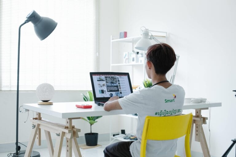 Young Man in White Shirt Sitting on yellow Chair Using Laptop eand studydesk with woorden legs